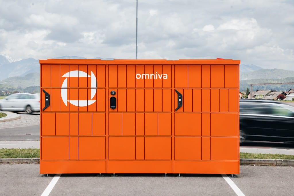 A large orange Omniva parcel machine in a car park